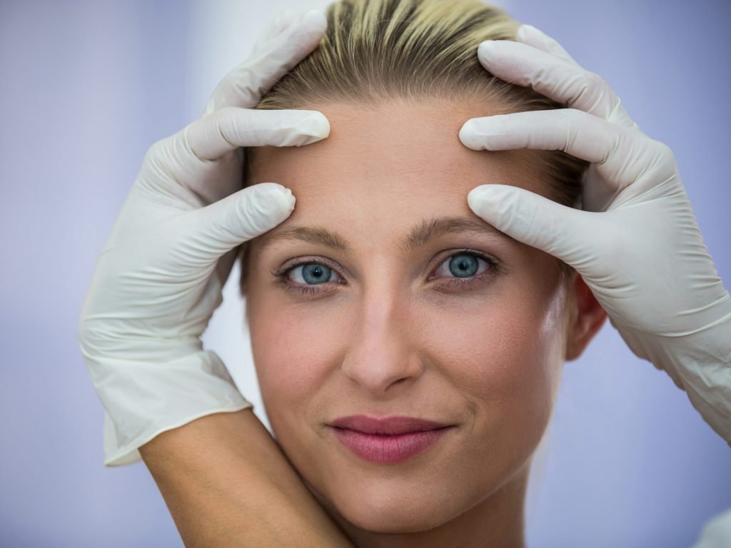 Doctor examining female patients face from cosmetic treatment